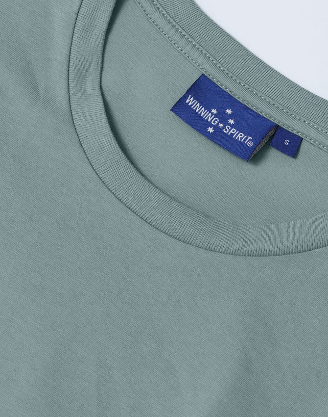 A close-up of a men's premium cotton short-sleeve T-shirt in a soft green hue, featuring a branded label.
