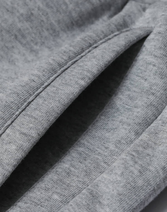 A close-up of grey unisex sweatpants featuring a soft, textured fabric and visible stitching details.