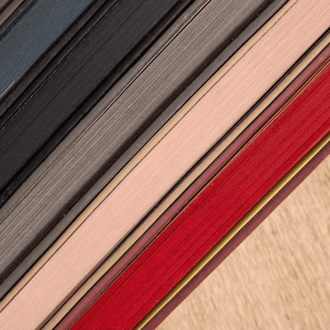 A selection of Bondi A5 Leather Notebooks in various colours, including black, grey, pink, and red, stacked together.