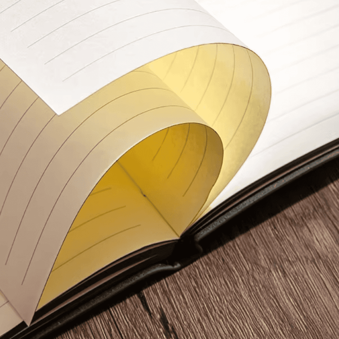 An A5 leather notebook featuring lined pages, with a yellow section visible, set on a wooden surface.