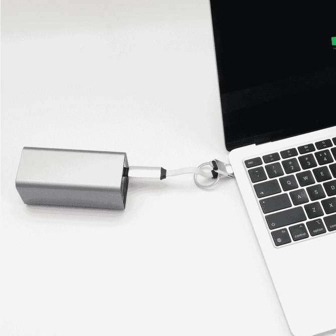 A silver 60W 3-In-1 aluminium charging cable connected to a laptop, featuring a logo on the cable.