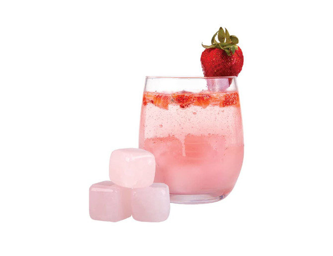 A drink glass filled with a pink beverage and strawberries, accompanied by three pale pink rose quartz gin stones.