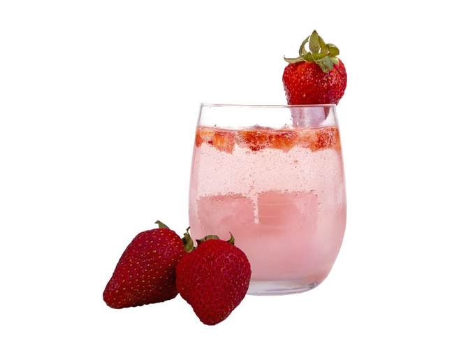 A drink glass filled with pink liquid, featuring ice and fresh strawberries, accompanied by three strawberries.