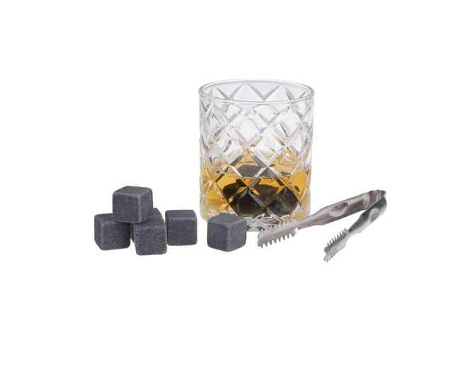 A whisky glass with amber liquid, grey whisky stones, and stainless steel tongs arranged nearby.