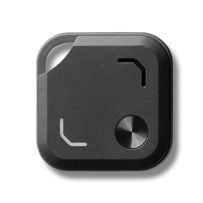 A black Bluetooth tracker featuring a metal button and a small opening, with a minimalist design.