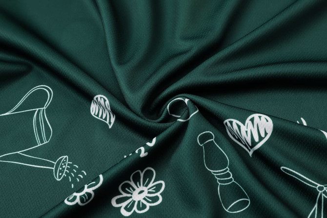 A close-up of dark green fabric featuring a pattern of white floral and gardening illustrations.