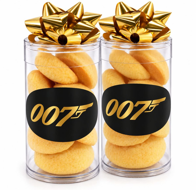 A clear tube containing traditional shortbread biscuits, topped with a gold bow and featuring a black label with a logo.