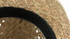 A straw hat with a woven design and a black fabric band around the edge. Features a logo.