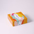 A brightly coloured gift box featuring abstract patterns and a logo on the lid. The box has a yellow background.
