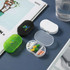 Three pill boxes in green, black, and white, displaying various pills inside a transparent compartment.