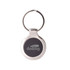 A metallic keyring with a circular design and a dark central area, featuring a branding logo.