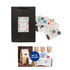 A small vertical black paper bag with a rope handle, accompanied by various decorative stickers.