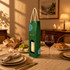 A green single bottle wine box with a rope handle, featuring a window and a logo. The setting includes dinnerware and food.