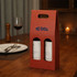 A double bottle wine box in red with circular cutouts, featuring a handle and a logo on the side.