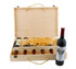 A vintage wooden wine box containing six drink bottles and one displayed bottle, with straw filling. The box is light-coloured.