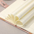 A close-up of a cream-coloured notebook with lined pages, featuring a pink leather cover and heart-shaped folded pages.