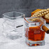 A whiskey glass set featuring square-shaped designs with one glass holding amber liquid and a cigar inserted.