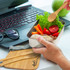 A stainless steel lunch box in silver containing salad and vegetables, accompanied by wooden cutlery on a wooden mat.