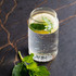 A clear glass filled with sparkling water, lemon slices, and fresh mint leaves, sitting on a dark marble surface.