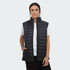 A woman is wearing a black puffer vest over a white t-shirt, featuring a logo and zip-up design.