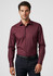 A maroon long sleeve button-up shirt with a fitted design and a logo. Styled with dark trousers.