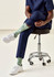 Unisex green socks with a playful design, featuring patterns, worn by a person seated on a stool.