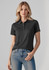 A dark grey women's short sleeve polo shirt with a collar and logo, paired with jeans.
