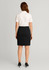 A black women's mid waist stretch chino skirt displayed on a model from the back, paired with a white polo shirt.