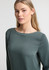 A women's boatneck top in green, featuring long sleeves and a smooth fabric. The design includes a subtle brand logo.
