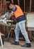 A man wearing men's stretch jeans in a light blue colour, working with a saw in a workshop environment.