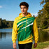 A vibrant unisex hoodie in yellow and green with a pocket, featuring a logo and dynamic pattern, set by a lakeside.