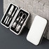 A sleek white manicure set case containing stainless steel tools like scissors, clippers, and tweezers.
