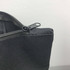 A grey nylon tote bag featuring a zipper closure and a metal zipper pull. It has a simple, minimalist design.