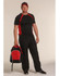 A man in a black and red athletic outfit holds a black and red backpack, wearing a matching cap.