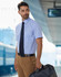 A men's short-sleeve button-up shirt in blue gingham check, paired with a tie and brown trousers. A bag is being held.