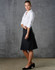 A black women's pleated skirt made from wool stretch, styled with a white shirt and black shoes, set against a grey background.