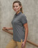 A grey women's poly/cotton polo shirt with short sleeves and a side split, displayed against a textured background.