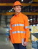 An orange long-sleeve work shirt featuring reflective stripes, worn by a smiling person in a construction setting.