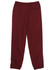 Burgundy track pants with an elastic waistband and cuffs, featuring a logo on the side.