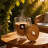 A drinkware glass cup with double walls and a bamboo lid, filled with steaming coffee, set on a wooden table.