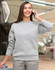 A grey crew fleece jumper with long sleeves, modelled by a person talking on a phone.