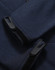 A close-up of a navy softshell hoodie featuring cuff details and a logo.