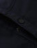 A close-up of a navy softshell jacket featuring a snap button and interior stitching details.