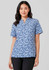 A woman wearing a short-sleeved tunic in a blue stardust print, featuring a collar and a relaxed fit.