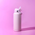 A drink bottle in a soft pink colour with a flip-top lid and a strap. It features a logo on the side.