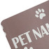 A pet feeding mat in a soft brown shade with white paw print designs and text. It features a branding logo.