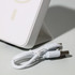 A white wireless charging power bank with a USB cable beside it, featuring a sleek, modern design.