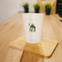 A translucent plastic stadium cup in light colour featuring a logo on its surface, placed on a wooden table.