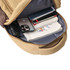 A tan canvas laptop backpack with an open compartment containing notebooks, a phone, and a drink bottle.