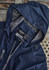 A navy unisex packable rain jacket featuring a hood, mesh lining, and a label. It includes a branding logo.